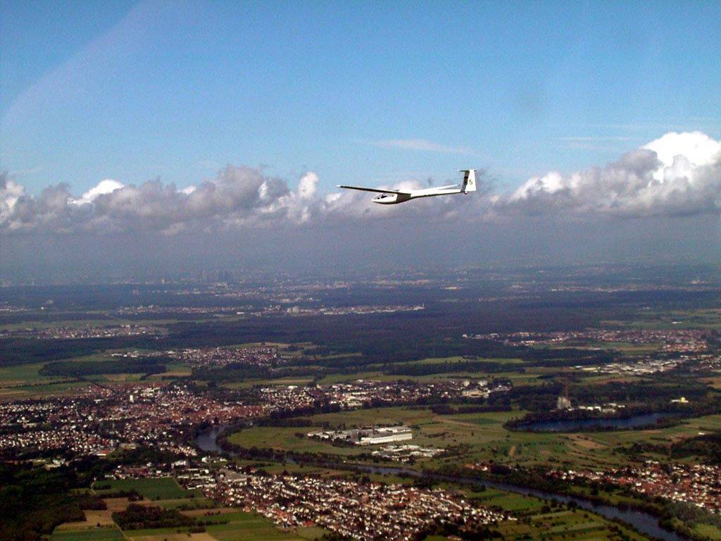 Distant glider soaring over a town